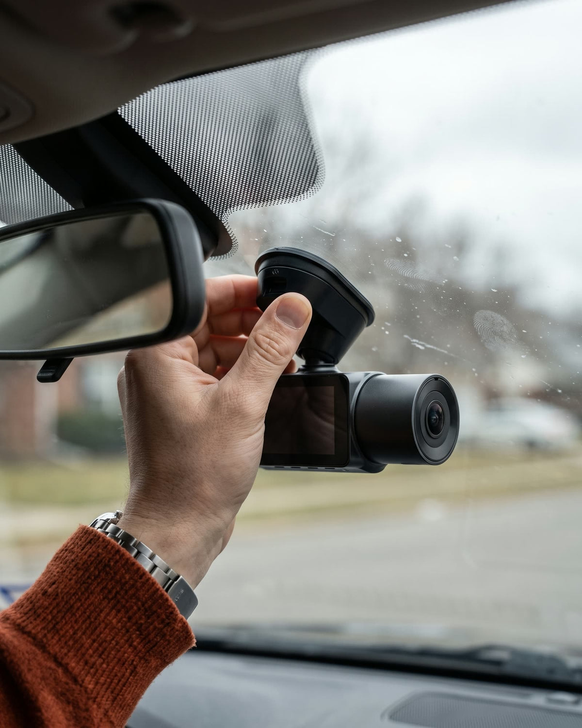 Hand pressing a dash cam mount onto a windshield